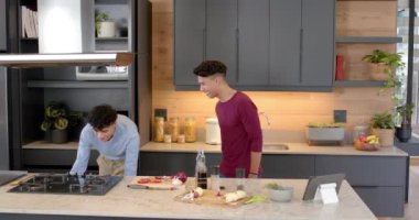 Yemek hazırlamak, evde sebze doğrayan ve el sıkışan çok ırklı eşcinsel çift. Yemek pişirme, takım çalışması, ortaklık, hazırlık, taze