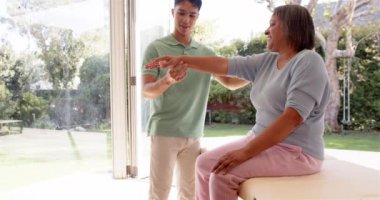 Kol egzersizlerinde yaşlı kadına yardım etmek, erkek fizyoterapist rehberlik hareketleri. Rehabilitasyon, fizyoterapi, sağlık, terapi, hareketlilik, yardım