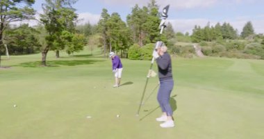 Kadın golfçüler bulutlu bir günde golf oynayıp golf sahasına top atıyorlar. spor, aktivite ve golf.