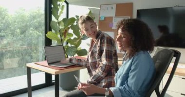 Evden çalışan kadınlar, dizüstü bilgisayar ve tablet kullanarak projede işbirliği yapıyorlar. Uzaktan çalışma, takım çalışması, teknoloji, işbirliği, ev ofisi, iş dünyası