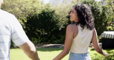 Bahçede birlikte yürürken, genç, çok ırklı bir çift açık havada güneşli bir günün tadını çıkarıyor, fotokopi çekiyorlar. Aşk, romantizm, doğa, mutluluk, güneş ışığı, birliktelik.