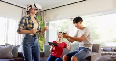 Aile izlerken ve gülerken sanal bir oyun oynayan bir kadın. Sanal gerçeklik, oyun, eğlence, teknoloji, eğlence, bağ