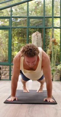 Dikey video: Yoga pratiği, cam evde köpek pozu veren adam. Zindelik, sağlık, egzersiz, rahatlama, esneme, farkındalık