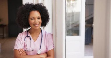 Pembe önlüklü, steteskoplu gülümseyen hemşire, pencerenin yanında duruyor. Sağlık, sağlık, meslek, sağlık, meslek, bakım