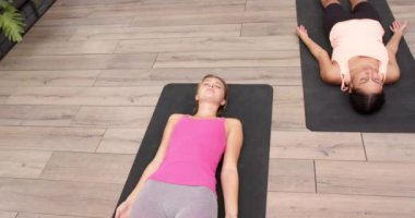 Yoga pratiği yapan, yoga minderleri üzerinde rahatlama pozu veren iki kadın. Sağlık, meditasyon, farkındalık, fitness, egzersiz, kadın sağlığı