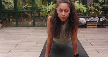 Yoga yapıyor, cam evde kadın yoga minderinde köpek pozu veriyor. Sağlık, zindelik, egzersiz, meditasyon, esneklik, farkındalık