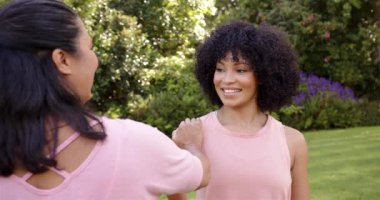 Parkta gülümseyen bir kadın, arkadaşı elini omzuna koyuyor, sohbetten zevk alıyor. Arkadaşlık, mutluluk, açık hava, bağlılık, refah, destek