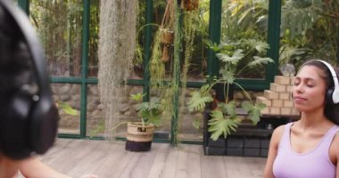 Yoga ve meditasyon pratiği, cam evde kulaklık takan bir kadın, fotokopi odası. Sağlık, farkındalık, fitness, egzersiz, rahatlama, açık hava