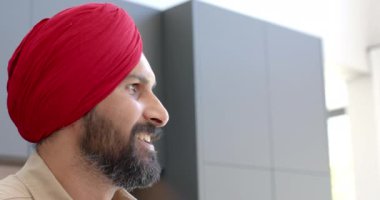 Kırmızı sarıklı gülümseyen adam başka tarafa bakıyor, evde eğleniyor. Mutluluk, rahatlama, kapalı alan, geleneksel, boş zaman, içerik