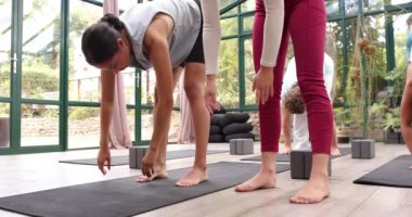 Yoga pratiği yapan, cam ev stüdyosundaki eğitmeninden rehberlik alan bir kadın. Sağlık, zindelik, meditasyon, esneme, refah, esneklik