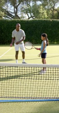 Dikey video: Tenis oynamak, sahada genç kızlara koçluk yapmak, tekniğe odaklanmak. Spor, tenis kortu, antrenman, akıl hocası, atletizm, raket