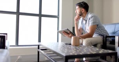 Derin düşünen, elinde tablet olan ve modern ofiste koltukta oturan adam, fotokopi uzayı. İş, teknoloji, dijital, profesyonel, düşünceli