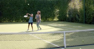 Tenis oynamak, kadın ve çocuk dışarıda güneş ışığında antrenman yapmak. Spor, egzersiz, açık hava, koçluk, aile, güneş ışığı.