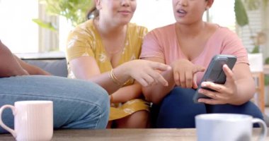 Bir grup arkadaş kanepede oturuyor, akıllı telefon kullanıyor ve bir şeyler tartışıyorlar. Arkadaşlık, teknoloji, sosyalleşme, sohbet, toplanma, boş zaman, değiştirilmemiş, yavaş çekim
