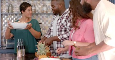 Çeşitli arkadaş grupları mutfakta birlikte yemek hazırlıyor, eğleniyorlar. Aşçılık, dostluk, takım çalışması, aşçılık, yaşam tarzı, bağlılık, çok kültürlü, değişmemiş, yavaş çekim