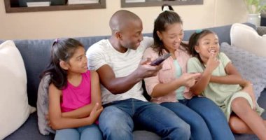 Birlikte televizyon izliyoruz, dört kişilik mutlu bir aile kanepede oturmuş gülümsüyor. Beraberlik, mutluluk, bağ, oturma odası, rahatlık, rahatlama.