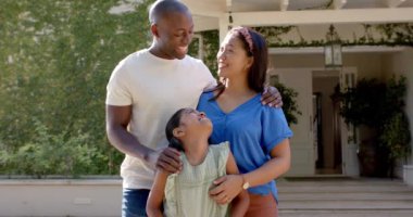 Üç kişilik gülümseyen aile evin dışında birlikte poz veriyor, kaliteli vakit geçiriyorlar. Beraberlik, açık hava, yaşam tarzı, bağlanma, mutluluk, rahatlık