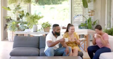 Kahve içmek, farklı arkadaşlar koltukta oturmak, rahat oturma odasında sohbet etmek, fotokopi çekmek. Arkadaşlık, birliktelik, rahatlama, sohbet, sosyalleşme, rahatlık.