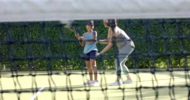Tenis oynuyorlar, anne ve çocuk birlikte dışarıda eğleniyorlar. Aile, spor, kaynaşma, eğlence, spor, etkinlik