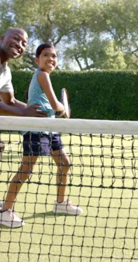 Dikey video: Tenis öğretmek, kızına kortta rehberlik etmek, raketi bir arada tutmak. Spor, koçluk, aile, bağ, eğlence, egzersiz