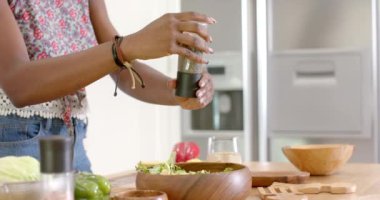 Baharatlı salata, modern mutfakta ahşap kaselerle taze yemek hazırlayan kadın. Aşçılık, aşçılık, sağlıklı beslenme, yemek hazırlığı, taze malzemeler, sebzeler.