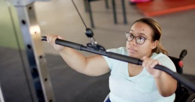 Tekerlekli sandalyede felçli bir kadın rehabilitasyon salonunda kablo makinesiyle egzersiz yapıyor. egzersiz, fizyoterapi, terapi, fitness, sağlık, güç, değişmemiş, yavaş çekim