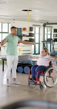 Dikey video: Rehabilitasyon merkezinde, direniş bandı, tekerlekli sandalyedeki kadın ve terapistle egzersiz. Fizyoterapi, egzersiz, sağlık, maluliyet, hareketlilik, terapi, yavaş çekim