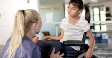 Rehabilitasyon merkezinde, tekerlekli sandalyede beyin felci geçiren bir kıza asistanlık yaparken, terapist gülümserken. fizyoterapi, sağlık hizmeti, etkileşim, yardım, tıbbi engellilik, değişmemiş, yavaş çekim