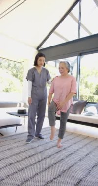 Dikey video: Fizyoterapist son sınıf öğrencisine evde bacak egzersizi yaptırıyor. Fizyoterapi, rehabilitasyon, sağlık, yaşlılık, yardım, terapi