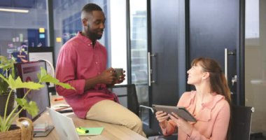 Modern ofisteki gülümseyen meslektaşlar, elinde kahve tutan bir adam ve tablet kullanan bir kadın. Takım çalışması, işbirliği, iş, profesyonel, işyeri, iş arkadaşları