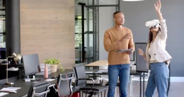 VR kulaklık kullanan bir kadın, modern ofiste elinde tablet bulunan meslektaşıyla etkileşime geçiyor. Teknoloji, iş, işbirliği, işyeri, iş arkadaşları, yenilik