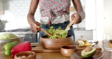 Ahşap çatal bıçak kullanan kadın mutfakta taze salata hazırlıyor. Yemek, sağlıklı, malzemeler, ev yapımı, vejetaryen, diyet