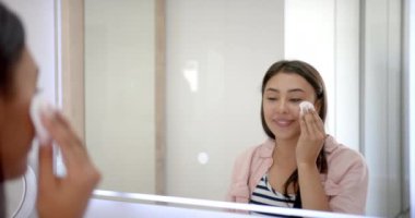 Cilt bakımı, pamuk ped kullanan ve banyo aynasında gülümseyen bir kadın. Güzellik, hijyen, kişisel bakım, sağlık, kozmetik, rutin