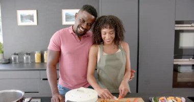 Mutfakta gülümseyen bir çift, sebze doğrayan bir kadın, ona sarılan bir adam. yemek, aşk, birlikte, mutluluk, ev