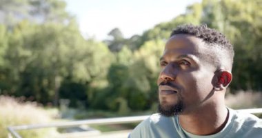 Gülümseyen adam açık havada güneşli bir günün tadını çıkarıyor arka planda yemyeşil bir ortam, fotokopi alanı. Güneş, mutluluk, doğa, rahatlama, rahatlama.