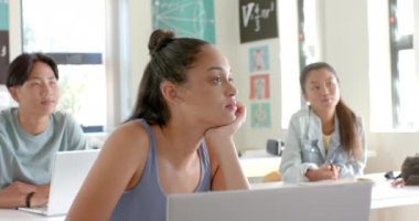 Lisedeyken, dizüstü bilgisayarla masada oturan genç bir kız sıkılmış görünüyordu. Eğitim, sınıf, öğrenci, öğrenme, teknoloji, can sıkıntısı