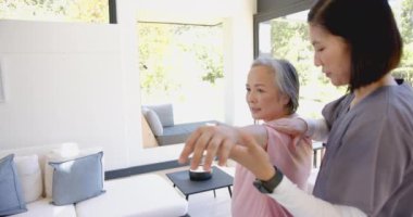 Omuz egzersizlerinde kıdemli Asyalı kadına yardım etmek, evde fizyoterapist rehberliği. Fizyoterapi, rehabilitasyon, sağlık, fizik tedavi, yaşlılar bakımı, hareketlilik