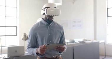 Modern ofis ortamında elinde tablet bulunan iş adamı VR kulaklığı kullanıyor. Teknoloji, yenilik, işyeri, kurumsal, profesyonel, sanal gerçeklik