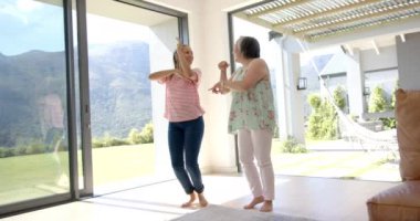 Asyalı büyükanne ve melez torun birlikte dans ediyorlar. İkisi de gündelik kıyafetler giyiyor, genç kadın koyu renk saçlı ve son sınıf öğrencisi kısa gri saçlı, değişmemiş.