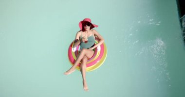 Havuzda dinlenmek, mayo giymiş bir kadın ve içkinin keyfini çıkarmak. Yaz, tatil, dinlenme, havuz başı, güneşlenme.