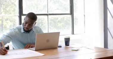 Ofiste çalışan, dizüstü bilgisayar kullanan ve evrakları inceleyen bir adam. İş, işyeri, üretkenlik, teknoloji, profesyonel, analiz