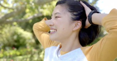 Ellerinle başını tutup, doğanın tadını çıkaran Asyalı bir kadına gülümsemek. Mutluluk, rahatlama, rahatlık, tazelik, yaşam tarzı.