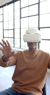 Dikey video: VR kulaklığı kullanan bir adam ofiste oturup sanal gerçekliği deneyimliyor. teknoloji, yenilik, oyun, dalgın, dijital, fütüristik