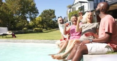 Havuz başında içkinin tadını çıkarmak, kıdemli arkadaşların dinlenmesi ve birlikte eğlenmesi, kopyalama alanı. Tatil, yaşam tarzı, eğlence, kaynaşma, yüzme, yaz