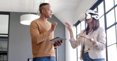 VR kulaklık kullanan bir kadın, meslektaşı ile ofisinde tablet tutarken etkileşime geçiyor. Teknoloji, işbirliği, işyeri, yenilik, işbirliği, etkileşim