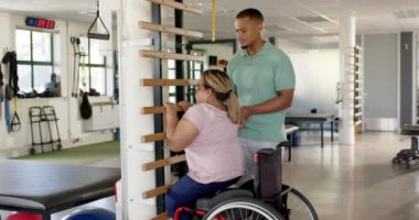 Terapi merkezinde rehabilitasyon sırasında tekerlekli sandalyede felçli bir kadına yardım etmek. Fizyoterapi, sağlık, sağlık, yardım, destek, iyileşme, değişmemiş, yavaş çekim