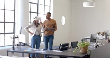 VR kulaklık kullanan bir kadın, modern ofiste elinde tablet olan bir meslektaşla işbirliği yapıyor. Teknoloji, yenilik, takım çalışması, işbirliği, iş dünyası, dijital