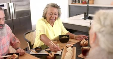 Birlikte yemek yemek, kıdemli arkadaşlar yemeğin tadını çıkarmak ve modern mutfakta gülmek. bağlanma, yemek, toplanma, sosyalleşme, sohbet, mutluluk