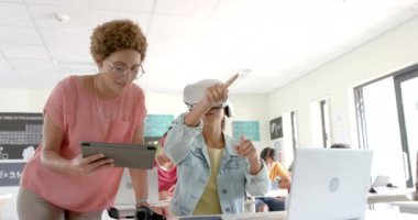 VR kulaklık kullanarak, lisede elinde tablet olan öğretmenle etkileşime giren bir öğrenci. Eğitim, teknoloji, sanal gerçeklik, sınıf, öğrenme, dijital