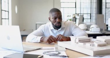 Dizüstü bilgisayar ve belgelerle birlikte inşaat modelinde çalışan bir mimar. Mimarlık, tasarım, planlama, ofis, yaratıcılık, planlar